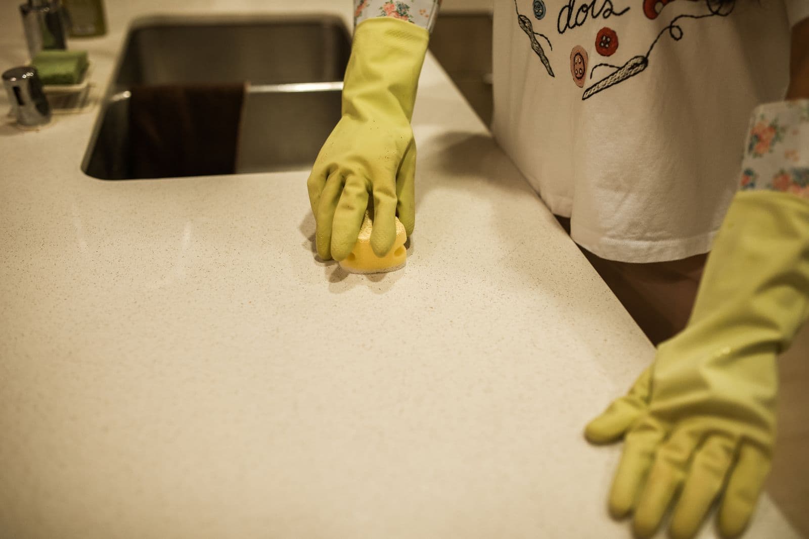 Mains gantées essuyant un plan de travail de cuisine