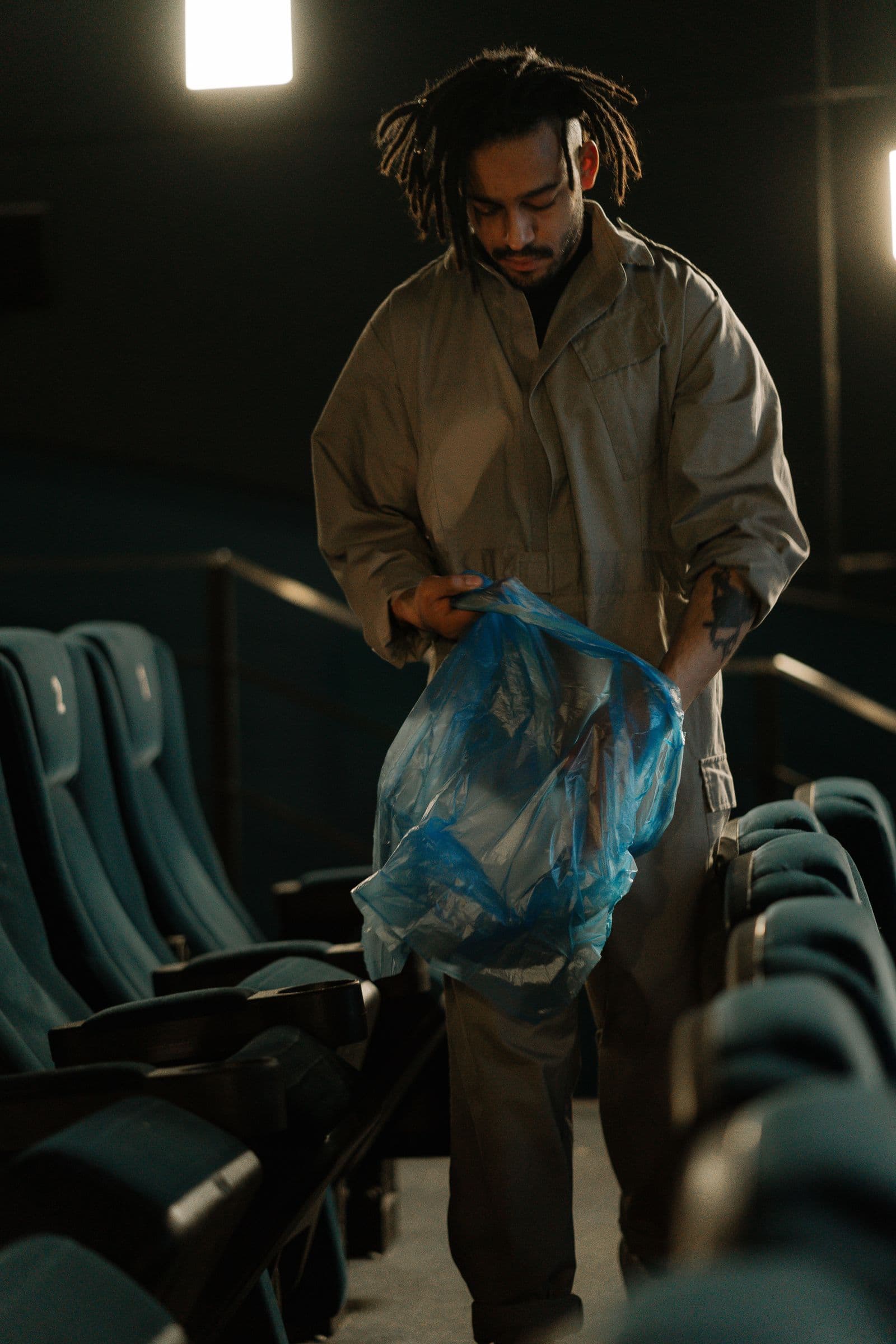 Agent en tenue de travail ramassant les déchets d'une salle