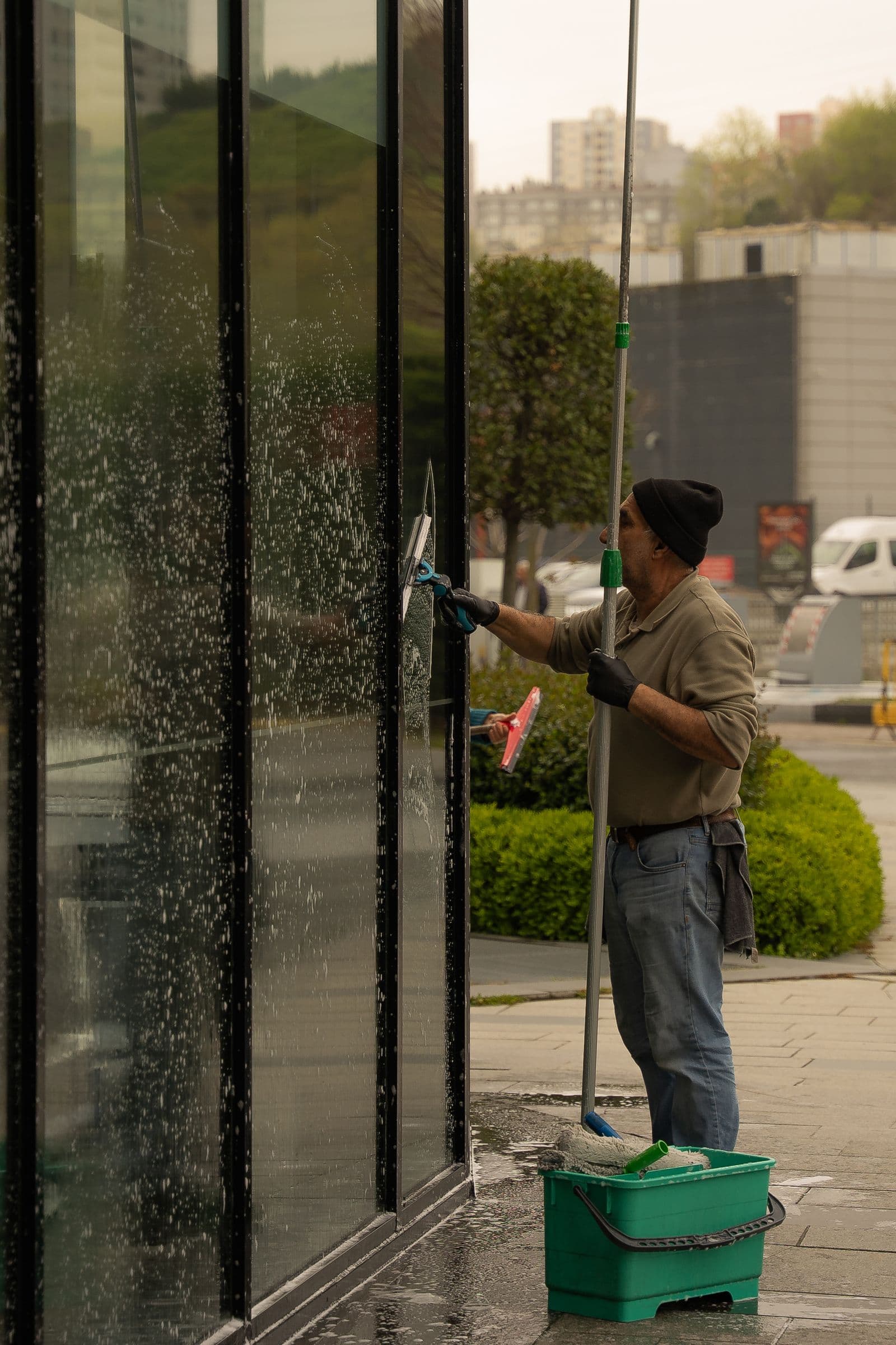 Lavage d'une vitre à la raclette sur une façade vitrée