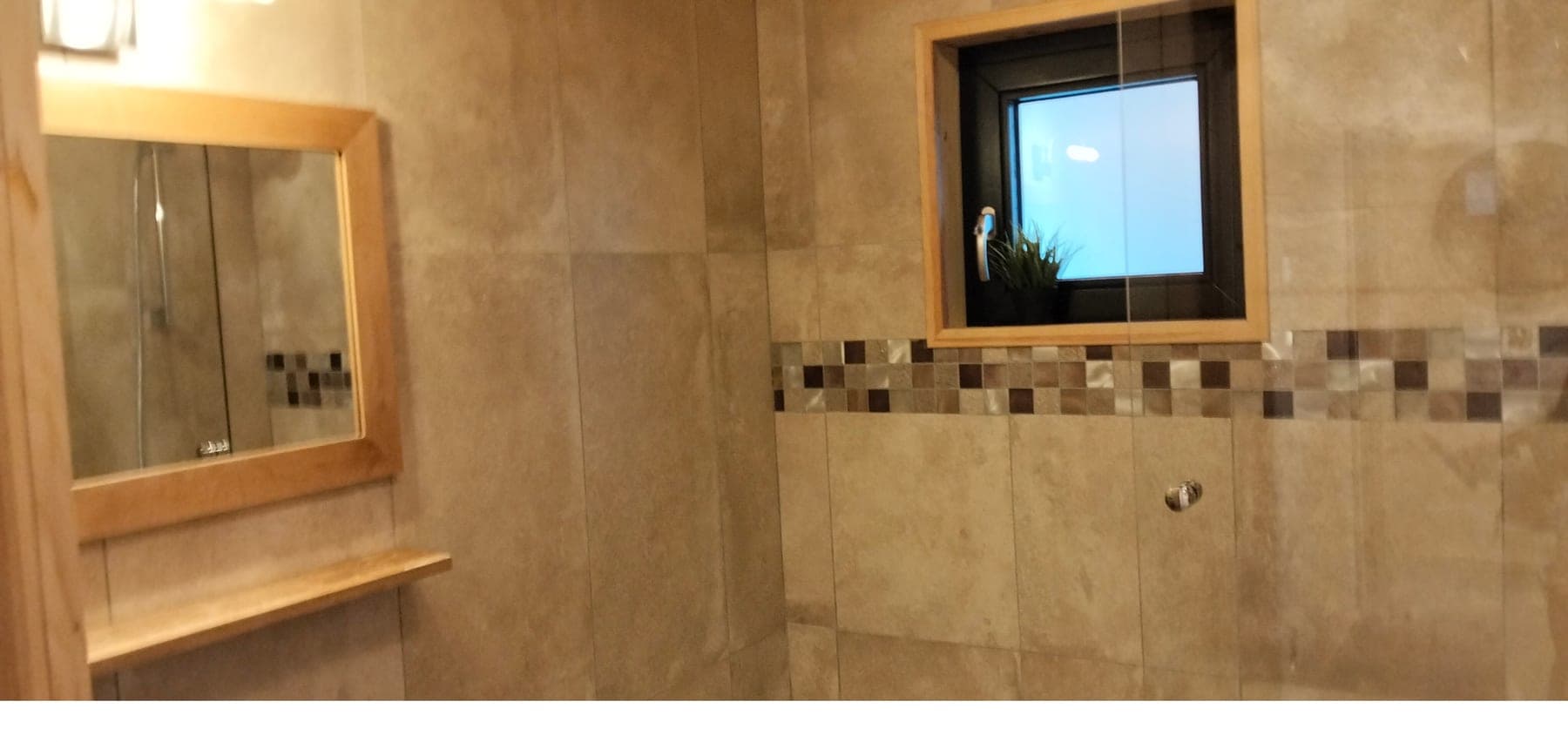 Salle d'eau d'un chalet : faïence, paroi de douche et miroir après passage